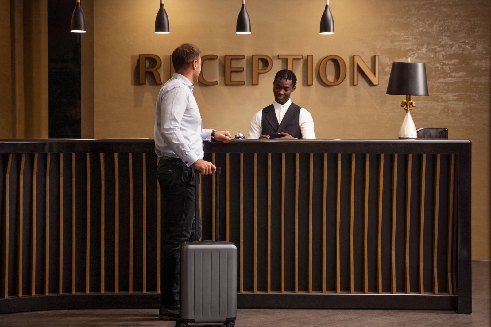 A guest with a suitcase checking in at a hotel reception desk